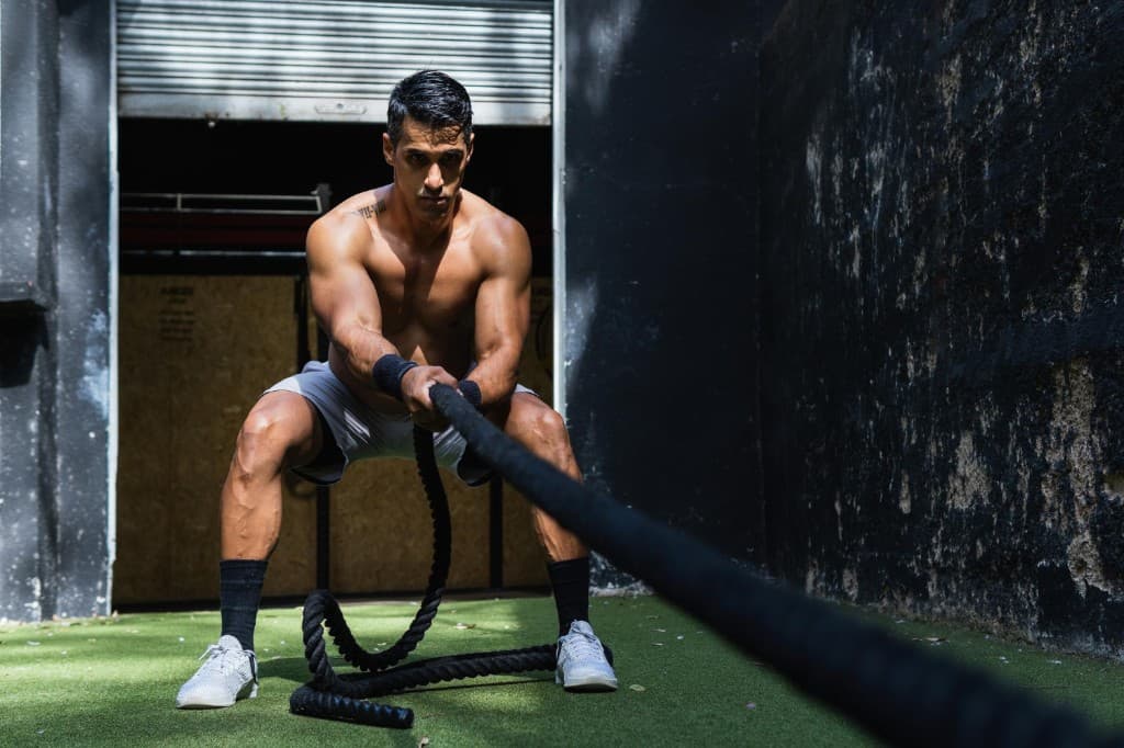 Athlète à la box en exercice avec battle ropes, effort intense — préparation HIROX
